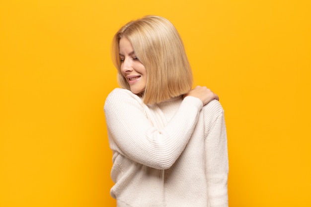 Blonde vrouw die zich moe, gestrest, angstig, gefrustreerd en depressief voelt, rug- of nekpijn heeft