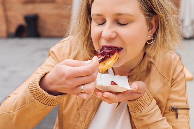 Blonde vrouw geniet van de smaak van gebakken kaas op lentedag in het stadscafé tijdens haar vakantie. rust en plezier. reizen en toerisme. levensstijl. het is een geweldige tijd. traditionele nationale keuken.