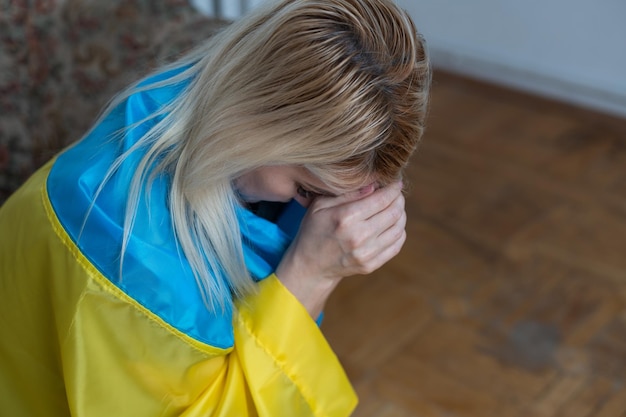 Blonde vrouw gewikkeld in de vlag van Oekraïne. Ondersteuning voor Oekraïne-concept