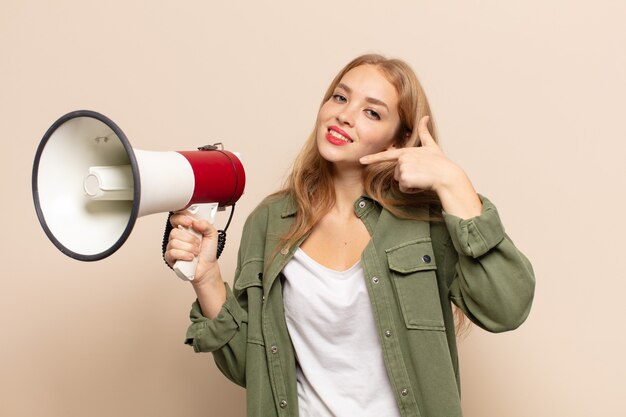 Blonde vrouw glimlachend vol vertrouwen wijzend op eigen brede glimlach, positieve, ontspannen, tevreden houding