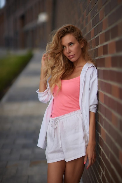 Blonde vrouw in een roze zomerjurk op een wandeling door de stad