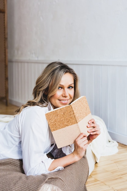 Blonde vrouw in een wit overhemd met een notitieboekje