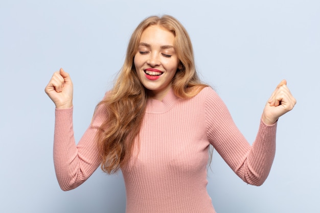 Blonde vrouw kijkt buitengewoon blij en verrast, viert succes, schreeuwt en springt