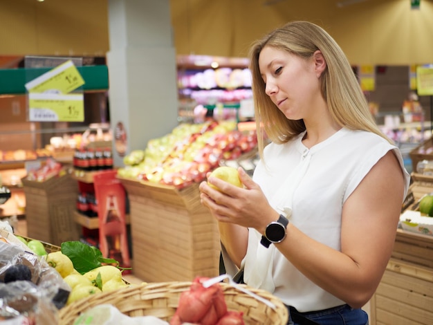 Foto blonde vrouw koopt fruit bij supermarkt