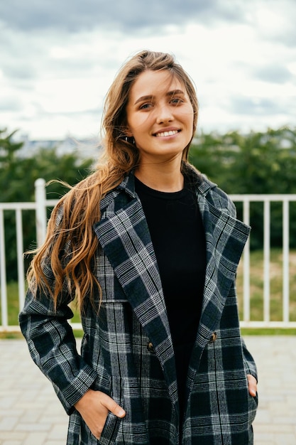 Foto blonde vrouw lacht naar de camera terwijl ze buiten staat op een winderige dag