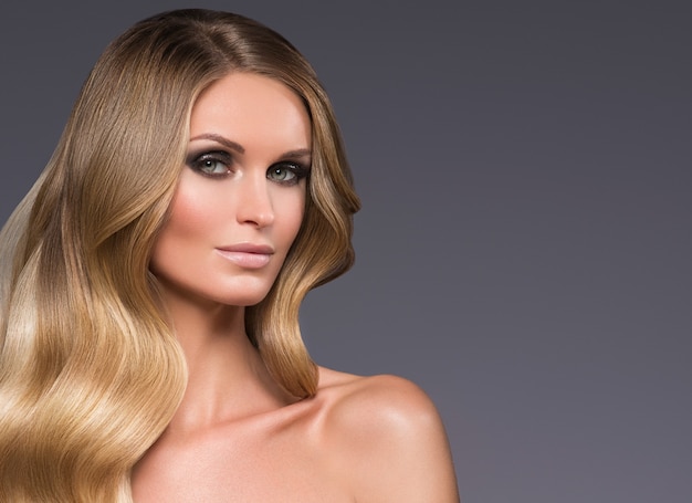 Blonde vrouw lang haar krullend natuurlijke mode make-up. Studio opname.