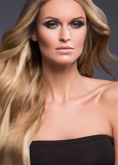 Foto blonde vrouw lang haar krullend natuurlijke mode make-up. studio opname.