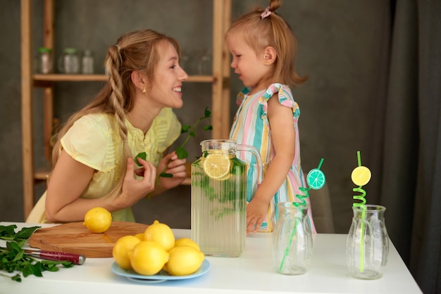 Blonde vrouw maakt limonade in de keuken terwijl haar dochter moeder haar baby kalmeert