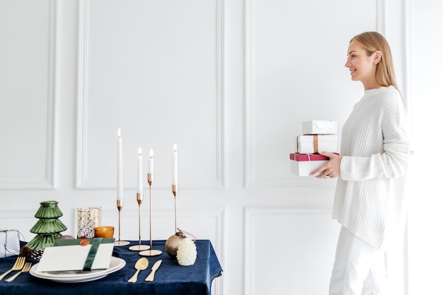 Blonde vrouw met cadeautjes dicht bij een eettafel