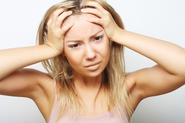 Blonde vrouw met een hoofd van de hoofdpijnholding