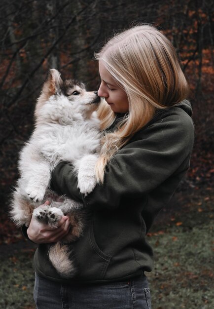 Foto blonde vrouw met een puppy die zoent.