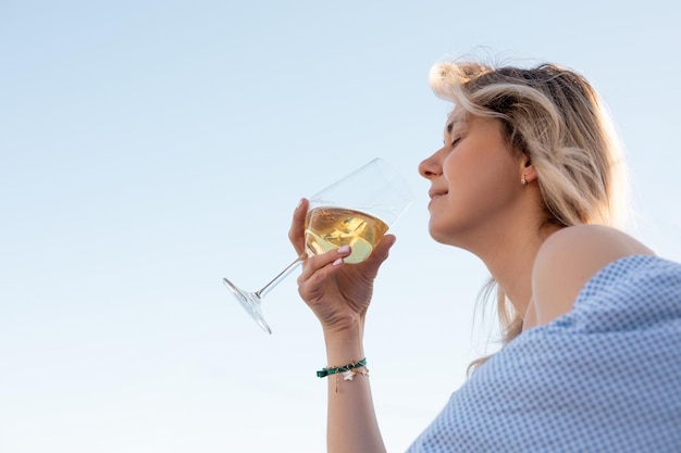 Blonde vrouw met gesloten ogen met smakelijke witte wijn in glas vreugde drinken op vakantie in reizen