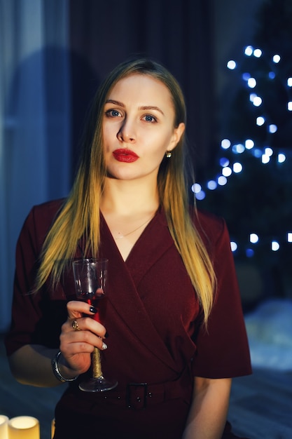 Blonde vrouw met glas champagne in huis Kerstboom Nieuwjaarsversieringen