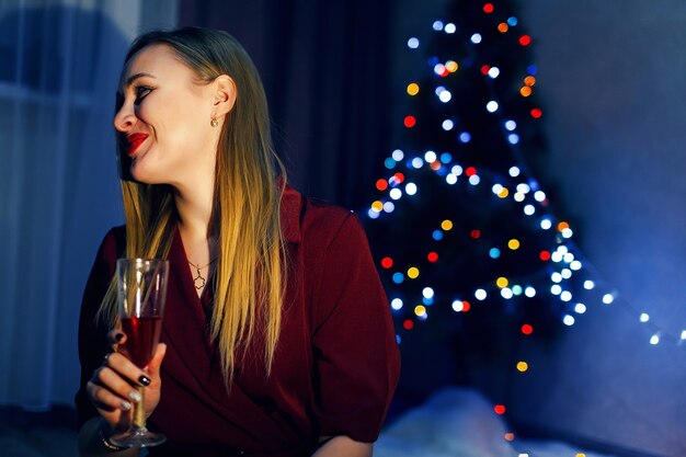 Blonde vrouw met glas champagne in huis Kerstboom Nieuwjaarsversieringen