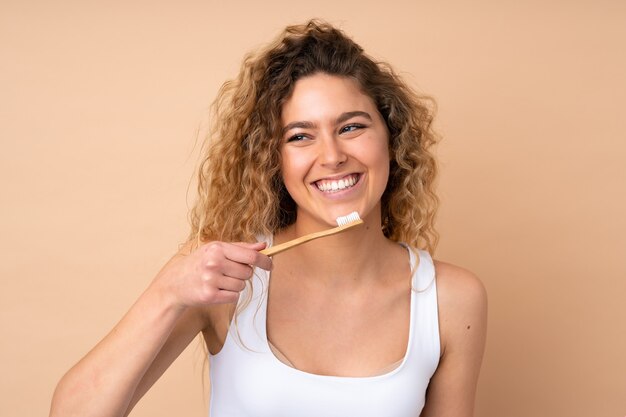 blonde vrouw met krullend haar geïsoleerd met een tandenborstel en gelukkige uitdrukking