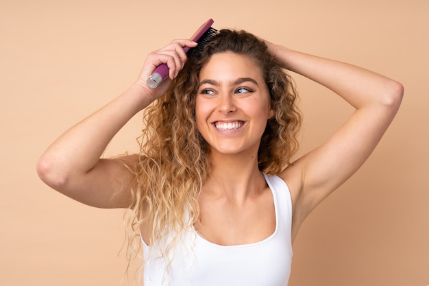 blonde vrouw met krullend haar geïsoleerd met haar kam