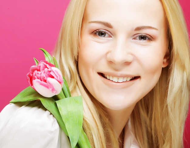 Blonde vrouw met roze tulp over roze