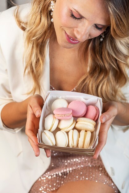 Foto blonde vrouw met traditionele franse maracoons, selectief focusbeeld