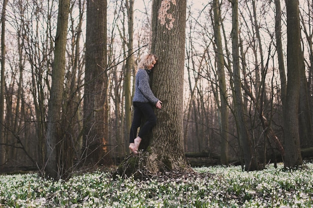 Foto blonde vrouw omhelst grote boomstam schilderachtige fotografie