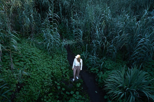 Blonde vrouw omringd door planten in het midden van de groene natuur