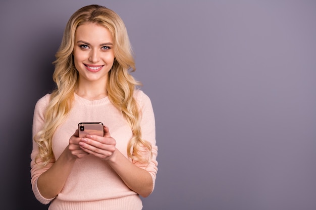 Foto blonde vrouw poseren in een trui tegen de paarse muur