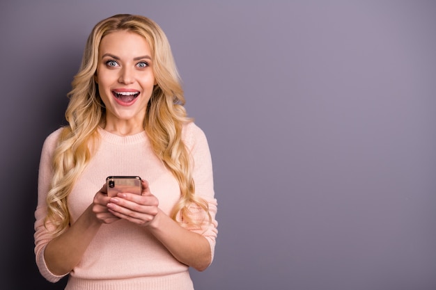 Blonde vrouw poseren in een trui tegen de paarse muur