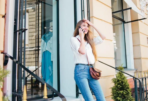 Blonde vrouw praten over de telefoon buitenshuis