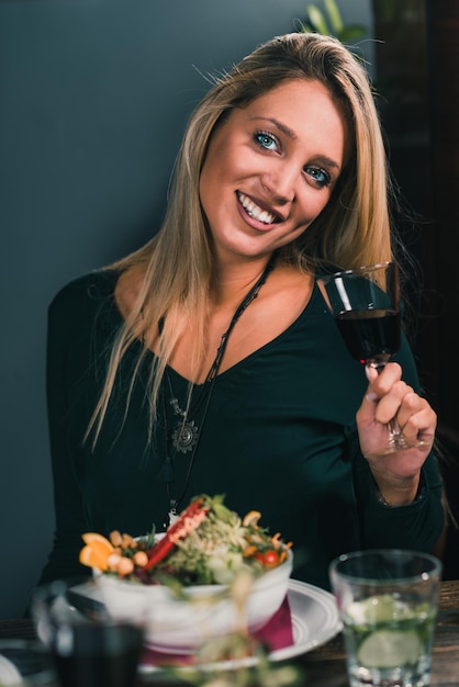 Blonde vrouw rode wijn drinken in restaurant