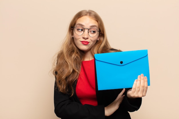 blonde vrouw schouderophalend, verward en onzeker gevoel, twijfelend met gekruiste armen en verbaasde blik