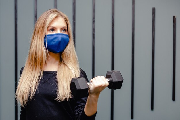 Blonde vrouw traint in de sportschool tijdens de pandemie