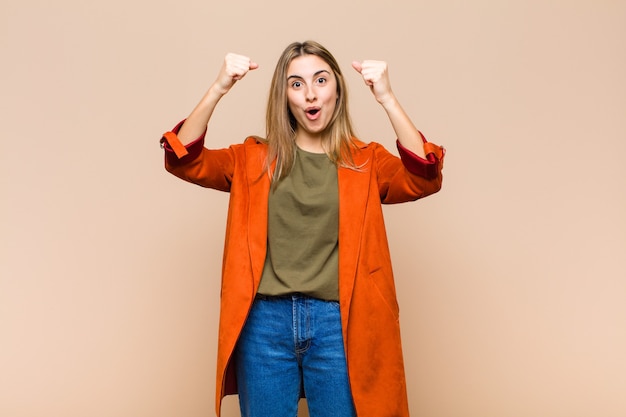 Blonde vrouw viert een ongelooflijk succes als een winnaar, kijkt opgewonden en blij en zegt: neem dat!