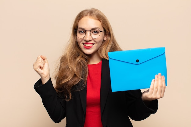 Blonde vrouw voelt zich geschokt, opgewonden en blij, lacht en viert succes, zeggend wow!