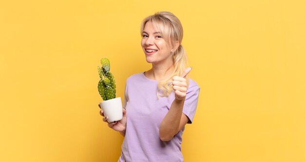 Blonde vrouw voelt zich trots, zorgeloos, zelfverzekerd en gelukkig, positief glimlachend met duimen omhoog