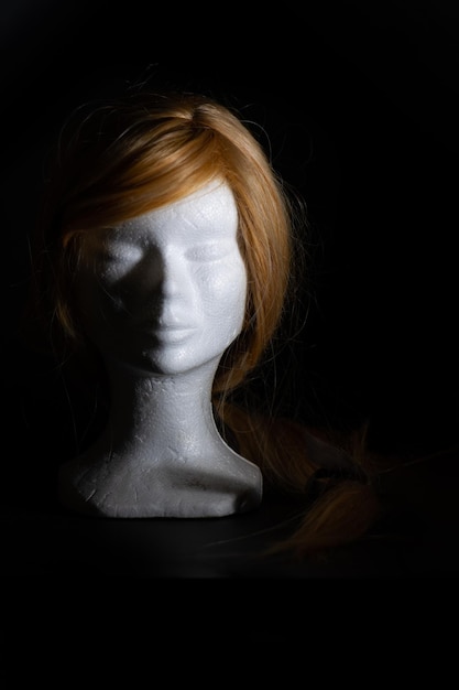 Photo blonde wig on a polystyrene head on a black background