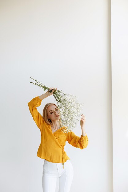 Blonde with flowers and autumn makeup on a light background. blogger