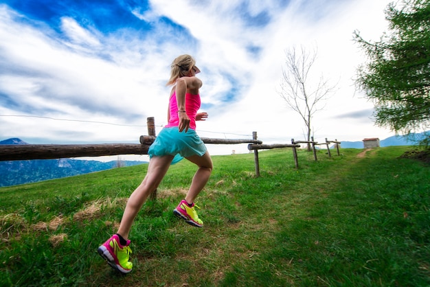 Foto l'atleta biondo della donna esegue un percorso di montagna nell'erba verde