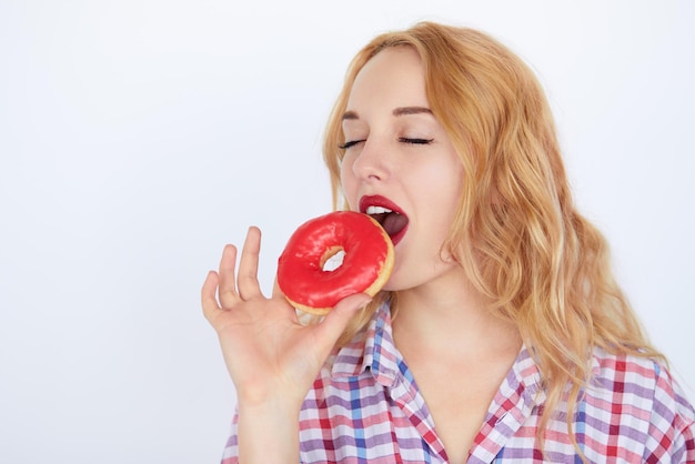 Blonde woman biting a red donut