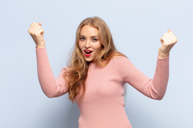 Photo blonde woman celebrating an unbelievable success like a winner, looking excited and happy saying take that!