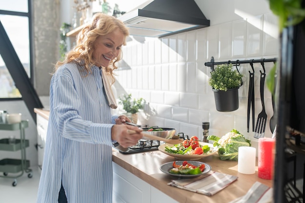 Blonde woman cooking and looking enjoyed