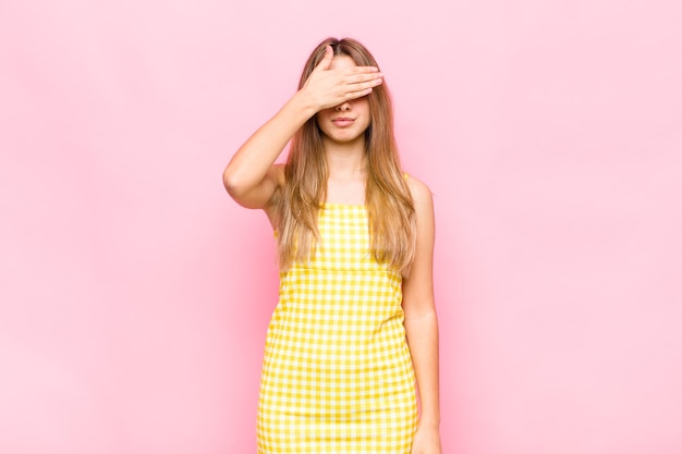 Blonde woman covering eyes with one hand feeling scared