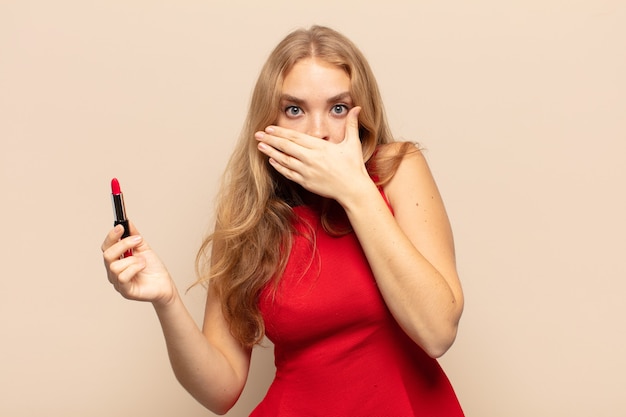 Blonde woman covering mouth with hands with a shocked, surprised expression, keeping a secret or saying oops