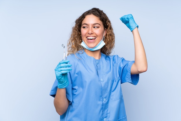 勝利を祝って分離されたツールを保持している金髪の女性歯科医