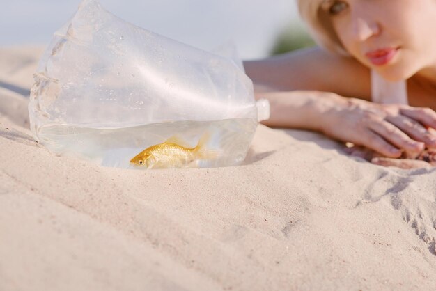 blonde woman in the desert with goldfish in her hands