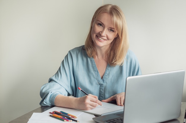 blonde woman draws in an album on an online lesson.