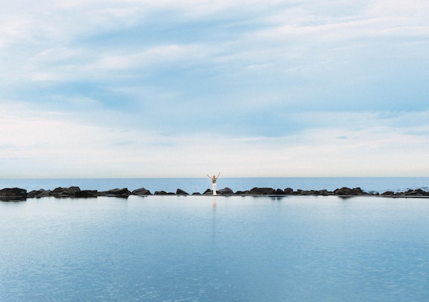 Blonde woman on the edge of a natural saltwater pool in front of the sea