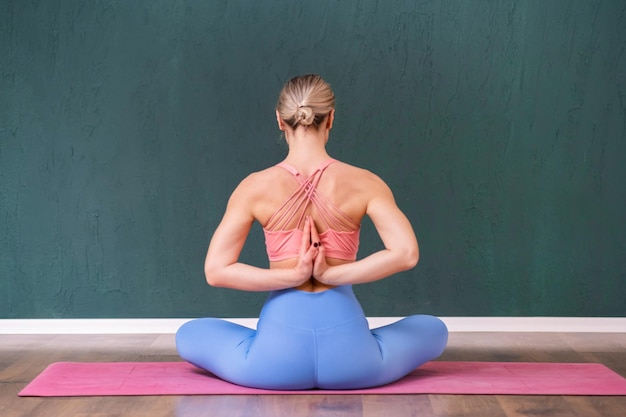 Photo blonde woman enjoying meditation at yoga class sitting in lotus pose on pink mat