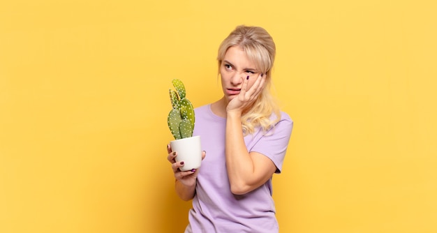 Blonde woman feeling bored, frustrated and sleepy after a tiresome, dull and tedious task, holding face with hand