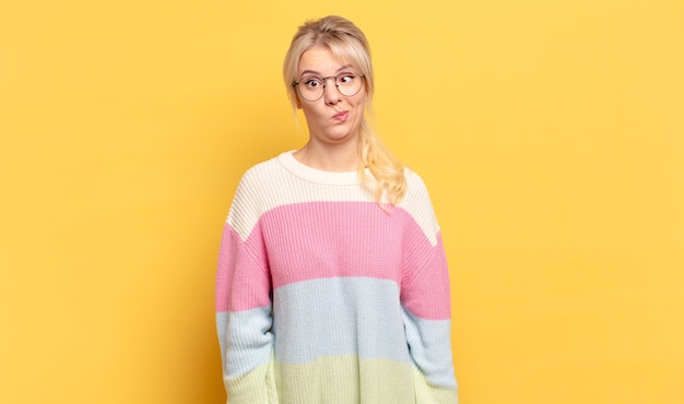 Blonde woman feeling confused and doubtful, wondering or trying to choose or make a decision