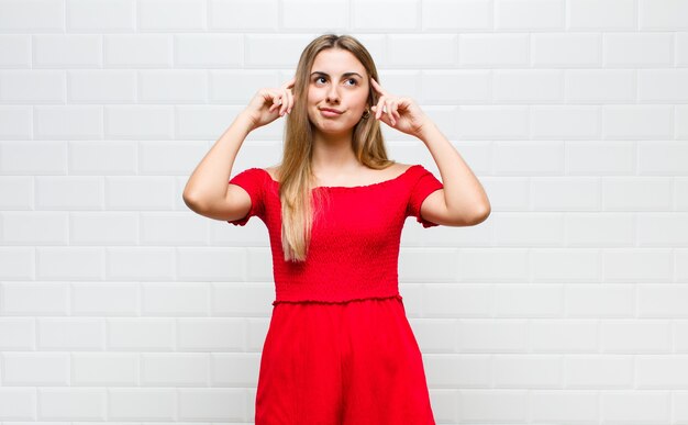 Blonde woman feeling confused or doubting, concentrating on an idea, thinking hard, looking to copy space on side