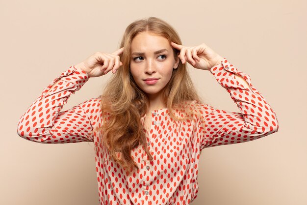 Blonde woman feeling confused or doubting, concentrating on an idea, thinking hard, looking to copy space on side